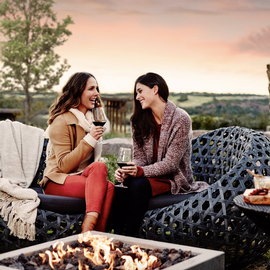 two women sitting on patio drinking wine