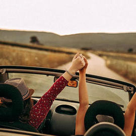 two girls in convertible holding hands